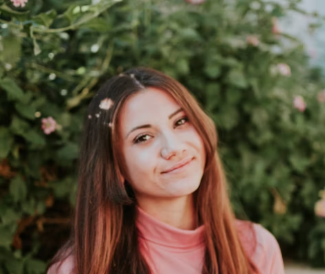 Woman with long brown hair smiling outdoors